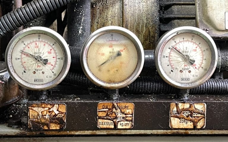 Three industrial pressure gauges showing service wear and failure