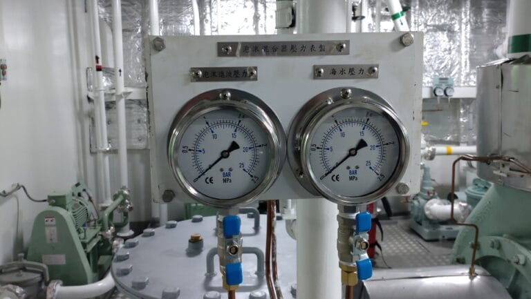 Two pressure gauges installed on a panel with valves and industrial pipework